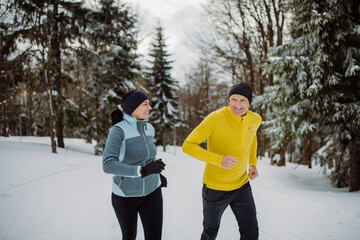 Senior couple jogging together in winter forest.