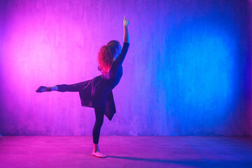 Obraz na płótnie Canvas Modern dance girl dancer dancing in neon light doing gymnastic exercises in studio, copy space.