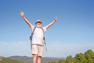 Active senior man standing and enjoying the top of the world opening arms - concept of no limit age...