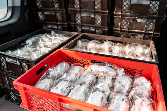 Trunk of delivery car packed with freshly handmade Christmas pies Christstollen, sweet goods packaged in containers in trunk of car near bakery on winter day. Wintertime holidays, present, gift