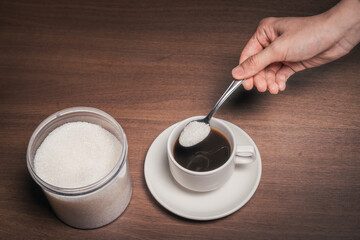 Adding sugar to a cup of black coffee