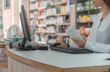 Mujer farmacéutica irreconocible, en la farmacia, buscando un producto de medicación, en el ordenador.