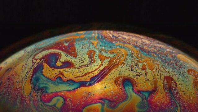 Fluid soap bubble looking like planets. Psychedelic colorful abstract art with urreal patterns of color in motion.