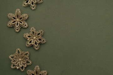 Holiday border made gold shiny christmas snowflakes on green background. Happy Christmas, Xmas and New Year concept. Top view, Flat lay, Copy space