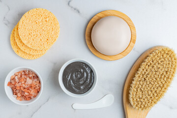beauty and spa concept - massagong body brush, clay mask, soap bar, konjac sponge and pink...