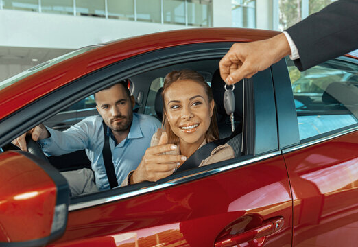 Young Couple Sitting Inside New Car And Holding Keys To It. Concept For Car Rental