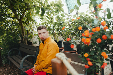 Portrait of caretaker with down syndrome in zoo, resting after work. Concept of integration people...