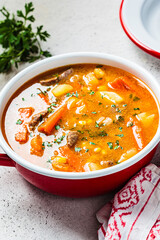Beef and vegetables soup or slow stew in red saucepan. Winter comfort food concept.