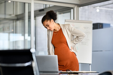 Black pregnant business woman suffering backache at modern office