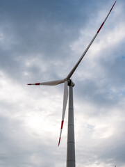 Blades on towers of wind turbines at sunset against cloudy sky. Close-up. Adyghe wind farm from many towers of wind turbines in field. Wind power complex of Rosatom.