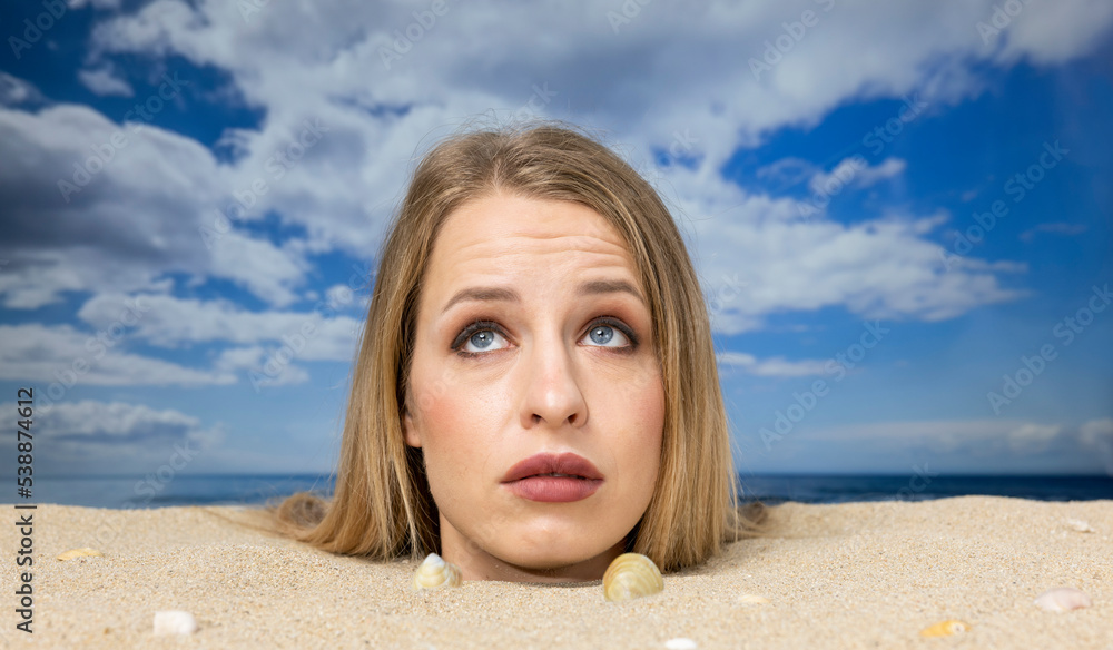 Wall mural Woman buried in sand on beach