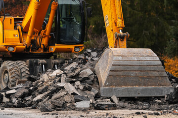 Fototapeta premium Detail view of an excavator dredger bulldozer used to destroy an old asphalt road. Industrial machines used in transportation industry.