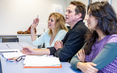 Adult Education: Questioning Learners. Mature students raising an issue with their teacher in class. From a series of related images on the subject.