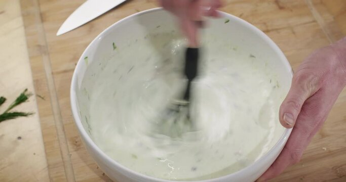 Home Chef Cooking, Preparing Bulgarian Cold Soup - Tarator. High Angle View, Stirring Yogurt Soup In A Mixing Bowl.