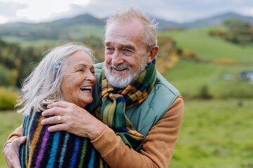 Portrait of happy senior couple walking in autumn meadow.