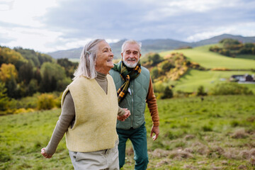 Happy senior couple walking in autumn meadow.