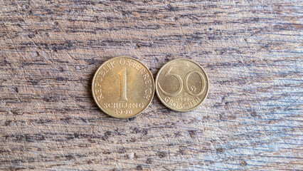 Aluminum bronze 1 shilling and 50 groschen 1990 coins, isolated on wooden background, Austria