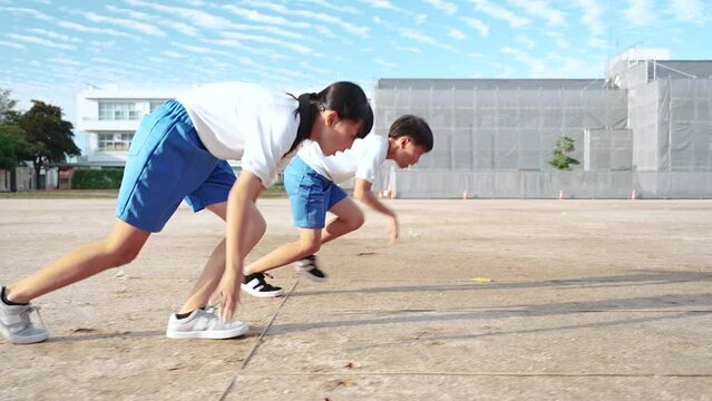 学校の校庭を走っている小学生の男の子と女の子
