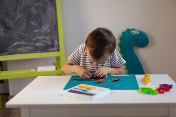 a little boy sculpts from plasticine on the table. Tactile activity, fine motor skills.