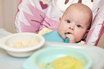 cute baby girl eating with spoon in kitchen
