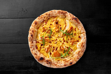 Pizza on thin dough with melted mozzarella, cheddar, chicken fillet and corn on black wooden background