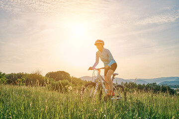 Cyclist Woman riding bike in helmets go in sports outdoors on sunny day a mountain in the forest. Silhouette female at sunset. Fresh air. Health care, authenticity, sense of balance and calmness.