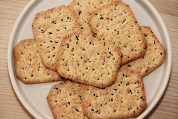 square salty diet crackers with black cumin seeds and quinoa in a glass plate