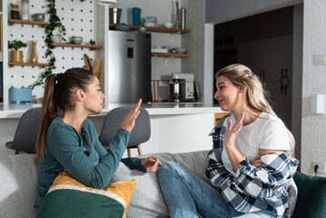 Young women lesbian couple LGBTQ+ roommates having argue due the infidelity and cheating. Two girls in relationship having difficulty caused by jealousy. Marriage problems concept. - obrazy, fototapety, plakaty