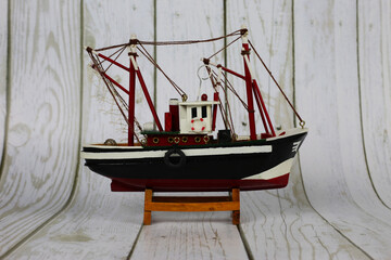Wooden model of a fishing boat on a stand. Decoration on the shelf, collecting ships.