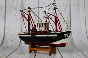 Wooden model of a fishing boat on a stand. Decoration on the shelf, collecting ships.