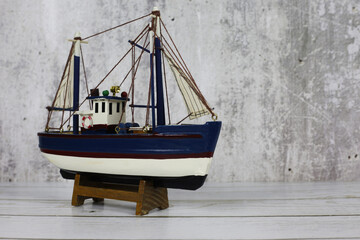 Wooden model of a fishing boat on a stand. Decoration on the shelf, collecting ships.