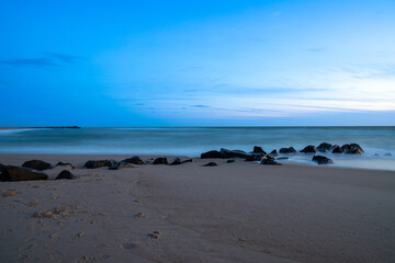 Fototapeta na wymiar Long exposure by the sea with rocks in the sand, blue hour. Denmark beach