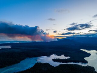 smoke rising over a hill in tasmania australia, from a bushfire in australia in summer.