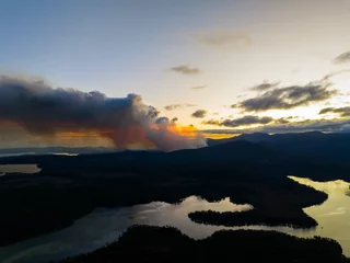 Crédence de cuisine en verre imprimé Mont Cradle smoke rising over a hill in tasmania australia, from a bushfire in australia in summer.