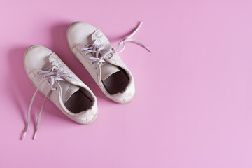 White leather sneakers isolated on pink background, Women's shoes, Fashionable casual shoes.
