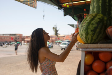 Young tourist buying one of the best juices and smoothies of Marrakech fresh fruit sold in the...