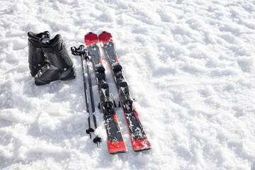 Mountain skis, ski boots and poles on bright alpine snow. Winter holidays. Extreme sport.  Vacation, travel content. Copy space