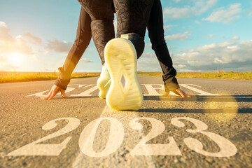 Female legs of runner at start on road close-up. Running into new year 2023, achieving goals and plans, success in startup. - obrazy, fototapety, plakaty