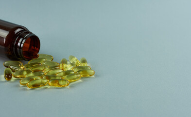 Omega 3 capsules in a brown bottle on a gray background. 