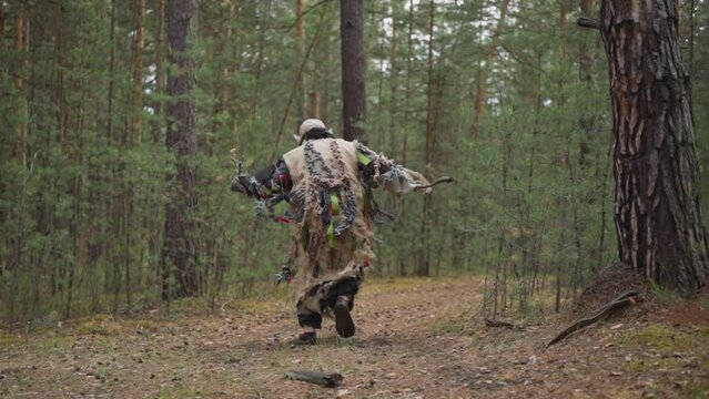 Ugly ogre in teared dirty clothes with wooden stick runs along road in deep forest backside view slow motion. Fairy tail creature. Legendary monster