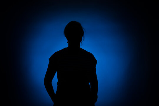 Silhouette Of A Woman On A Round Blue Spot On A Black Background