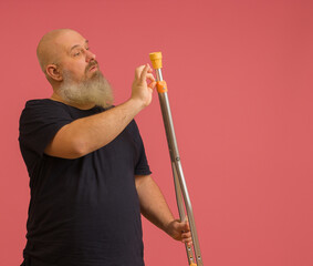 a man with a gray beard twists a bolt on a crutch on a colored background with copy space