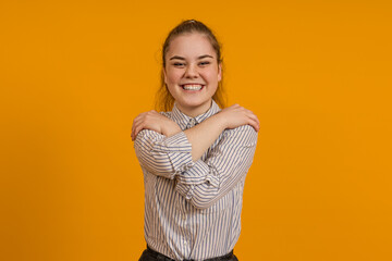 happy smiling girl hugging herself on color background