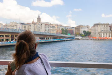 Fototapeta na wymiar Tourist woman looking to the Galata Tower in a ferry on Bosphorus