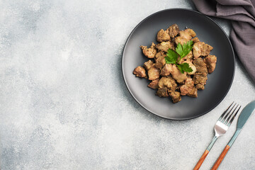 Fried or baked chicken liver with onion and sauce, green parsley leaves on a plate. Meat dish enriched with iron. copy space