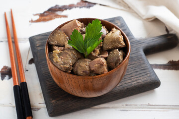 Fried or baked chicken liver with onion and sauce, green parsley leaves on a plate. Meat dish enriched with iron.