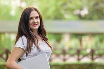 Happy young woman with laptop in the park.