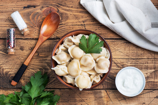 Traditional pelmeni, ravioli, dumplings filled with meat on plate, russian kitchen. Wooden rustic background, copy space.