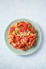 Penne pasta with chicken, tomato sauce and parsley leaves, overhead flat lay shot with copy space