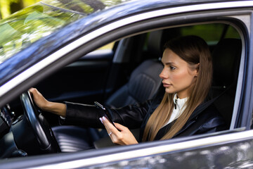 Fototapeta na wymiar Business woman sitting in car and using her smartphone.